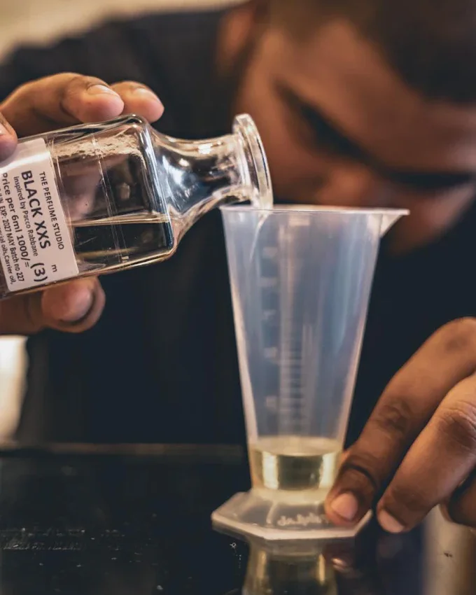 A perfumer decanting a composition into a glass measure